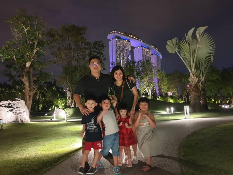 A family smiles for a photo in front of the iconic Marina Bay Sands in Singapore, showcasing a memorable moment together.